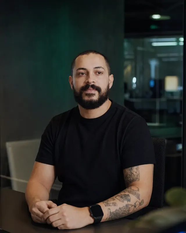 Felippe Cassiano, cofundador da Draivv, sentado à mesa do escritório.